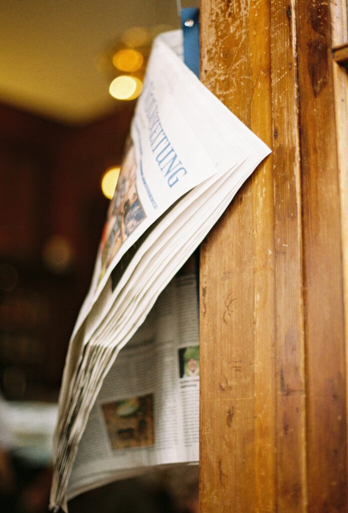 pexels-brcunel-32094623 Eine Zeitung hängt in einem Zeitungshalter, wie in einem Café.